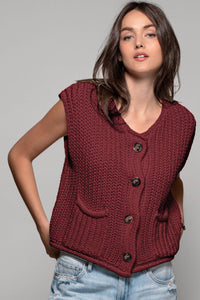 Woman wearing a red knitted vest against a gray background