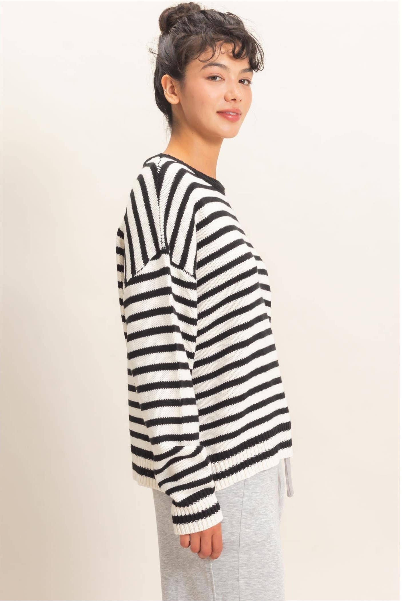 Side view of women's black and white striped knit sweater with long sleeves and soft comfortable fabric.