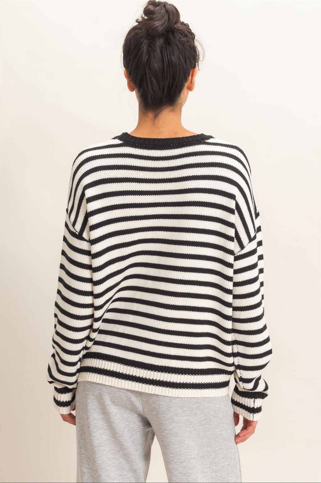 Back view of black and white striped relaxed fit sweater with ribbed hem and cuffs.