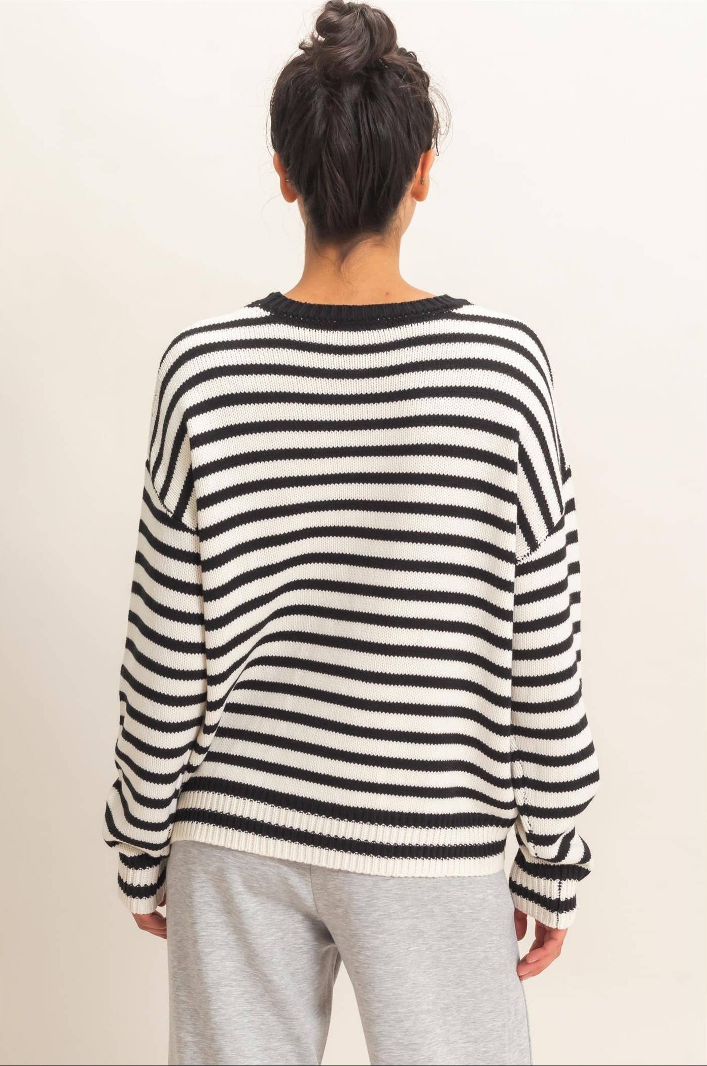 Back view of black and white striped relaxed fit sweater with ribbed hem and cuffs.