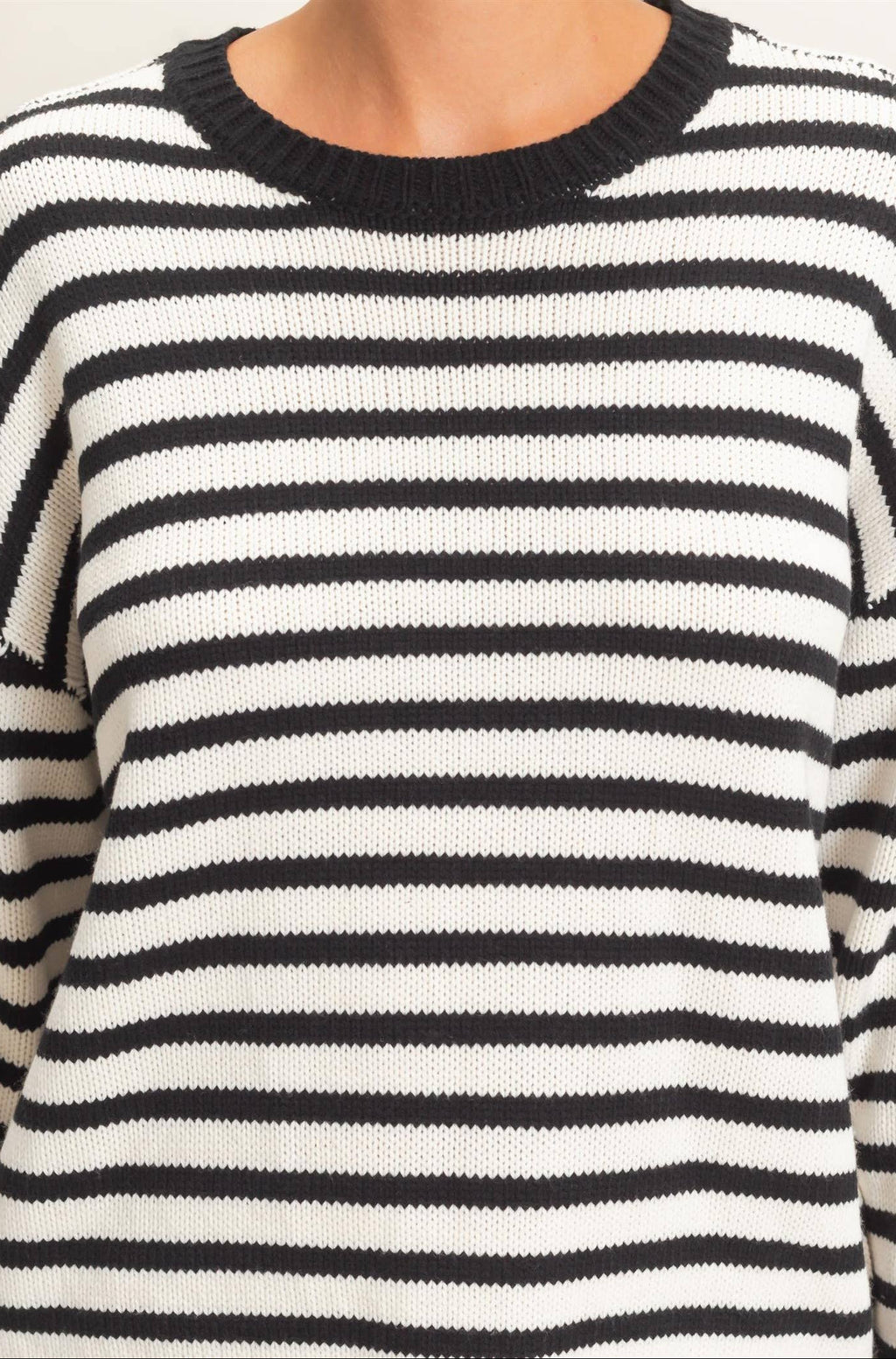 Close-up of crew neckline on a black and white striped knit sweater for women.