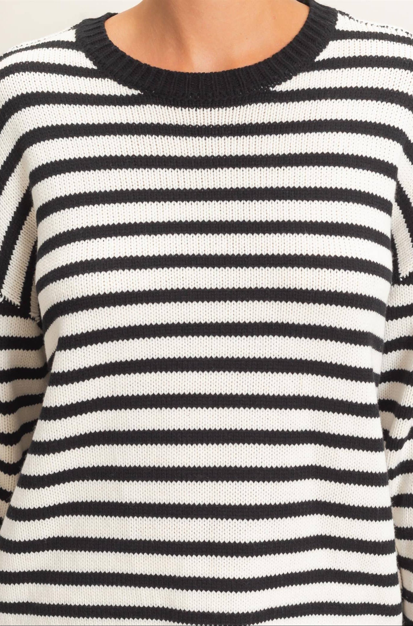 Close-up of crew neckline on a black and white striped knit sweater for women.