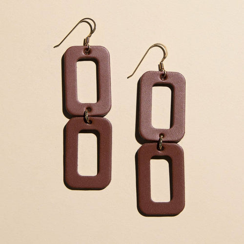A pair of rectangular drop earrings with a matte dark reddish-brown finish and gold-tone fishhook wires, displayed on a light beige background.