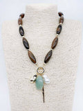 Brown natural stone necklace with pearl and green stone charms.