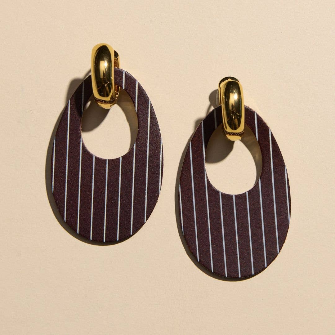 A pair of teardrop-shaped drop earrings with a dark brown and black pinstripe pattern, featuring gold-tone metal hoops at the top, displayed on a light beige background.