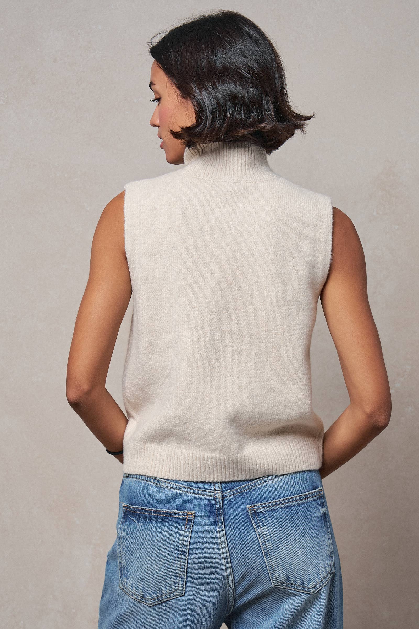 Crystal embellished sleeveless mock neck knit top.