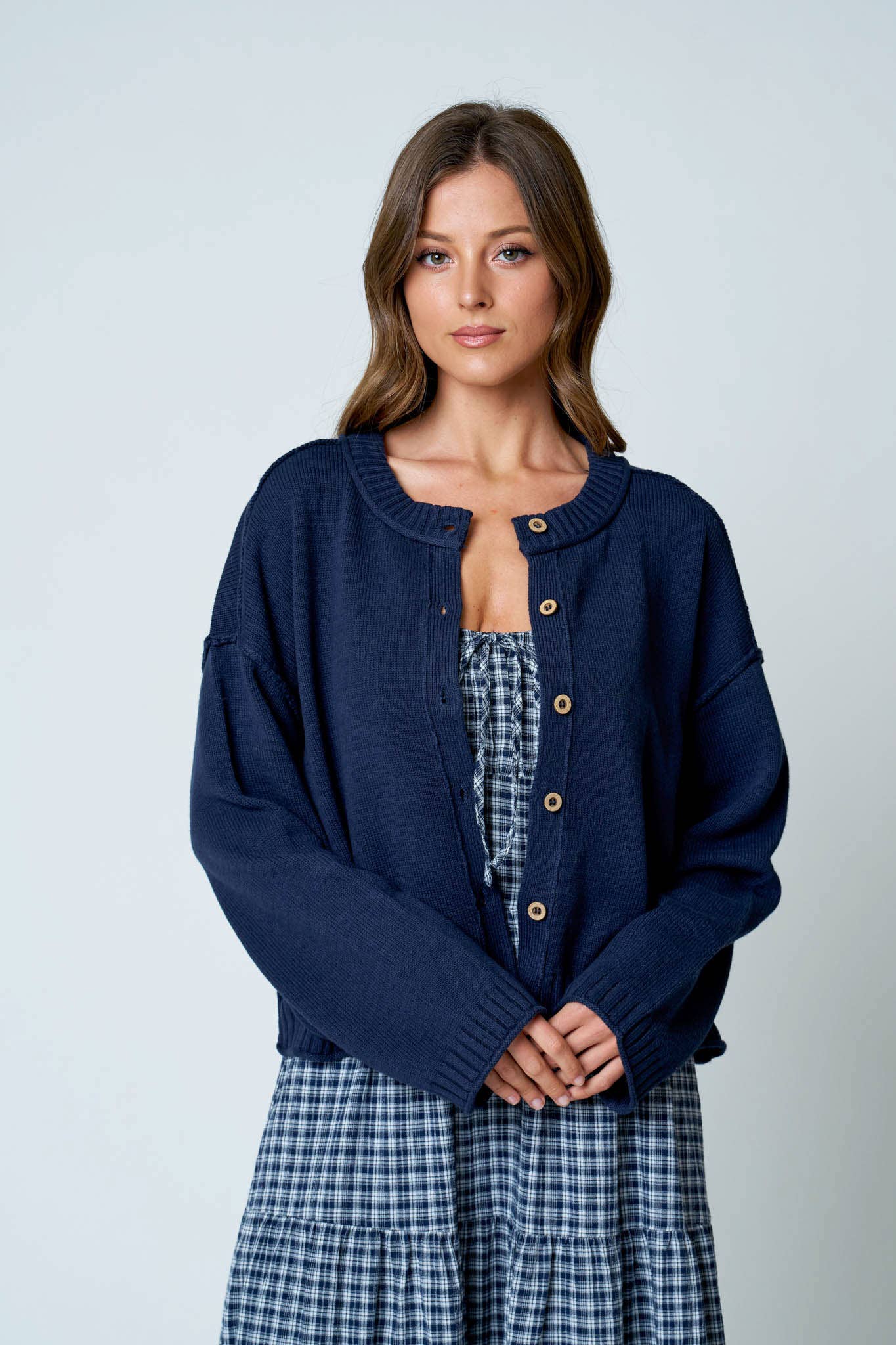 Women's navy button down knit cardigan with raw edge trim, crew neckline, and relaxed fit.
