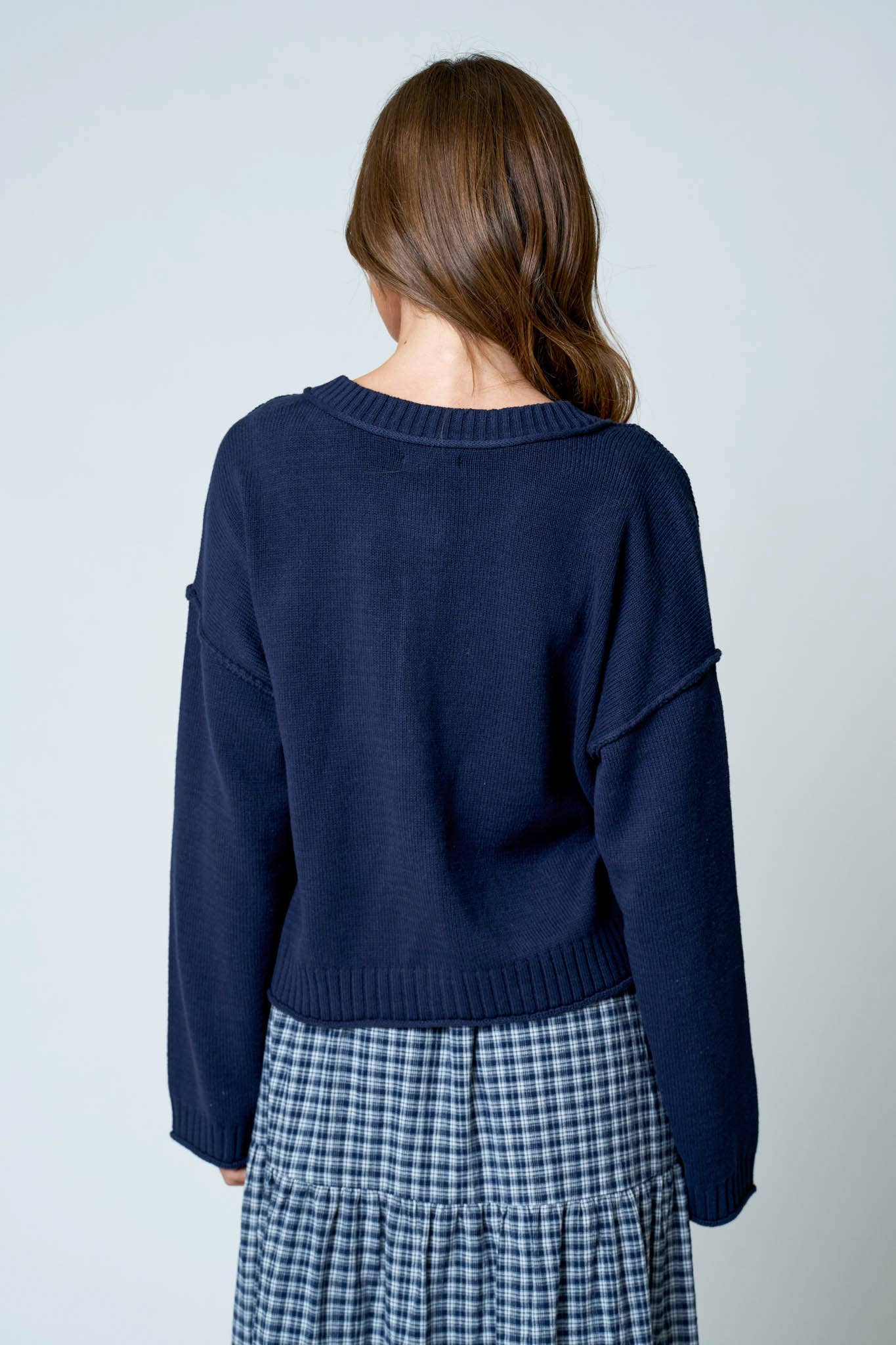 Back view of a navy relaxed fit cardigan sweater with drop shoulders and long sleeves.