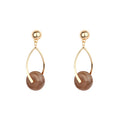 Women's gold dangle earrings with brown stone circle detail.