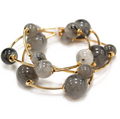 A gold-plated multi-strand beaded bracelet featuring smooth, polished gray and black marbled beads, displayed on a clean white background.