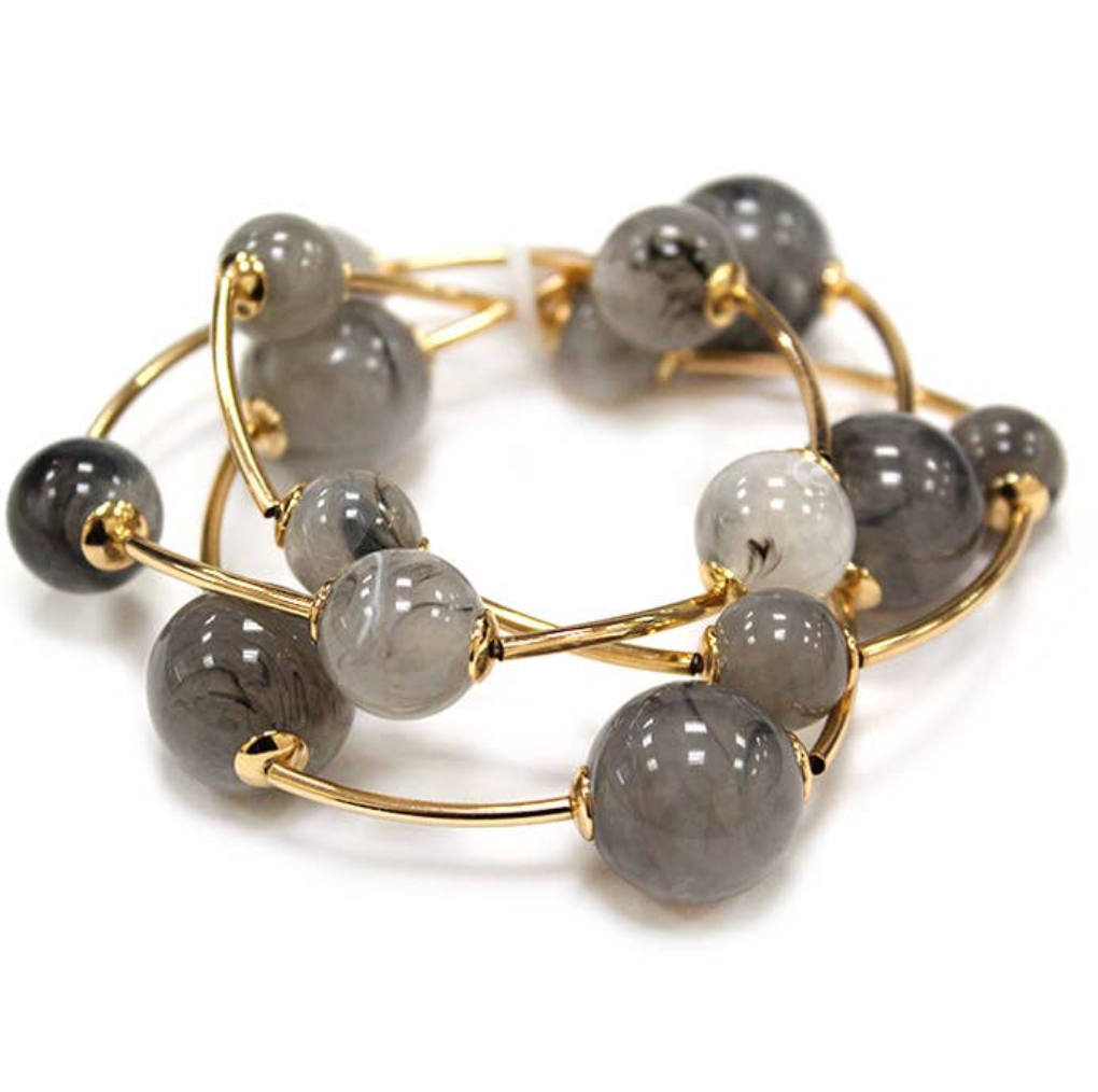 A gold-plated multi-strand beaded bracelet featuring smooth, polished gray and black marbled beads, displayed on a clean white background.