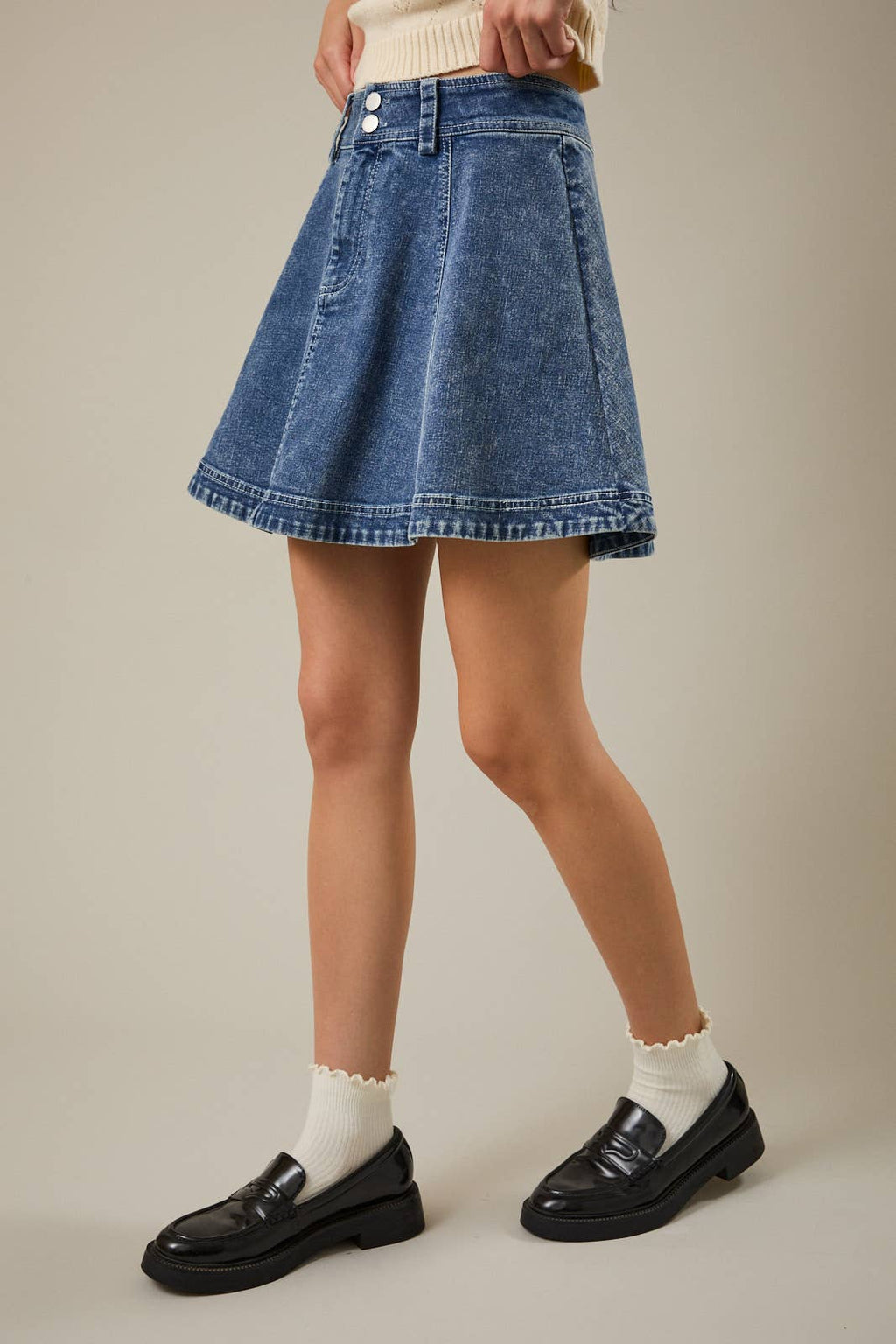 Side view of a women's medium wash flare denim skirt with a high-rise waist and feminine silhouette.