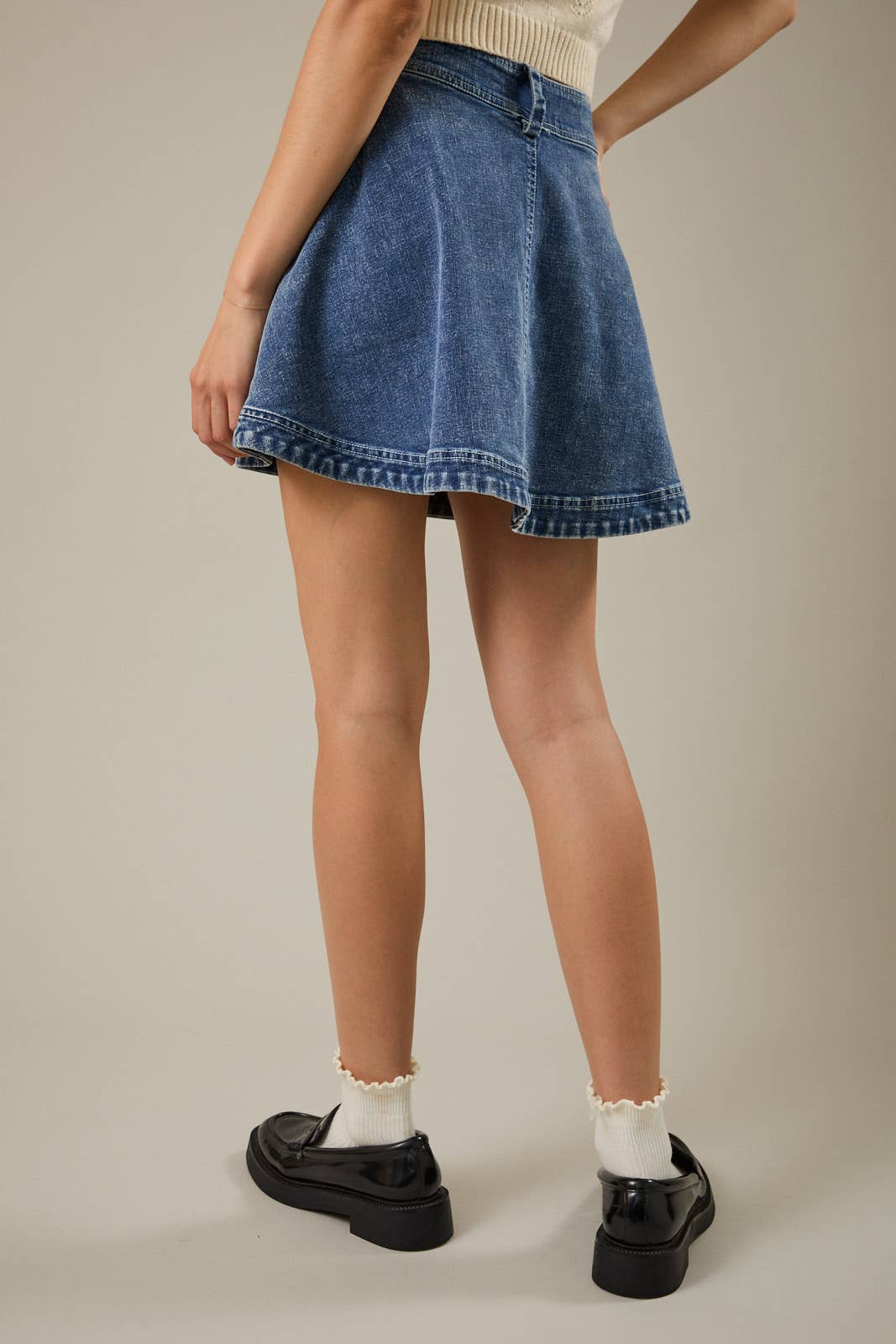 Back view of a medium wash high waist flare denim skirt with classic denim styling.