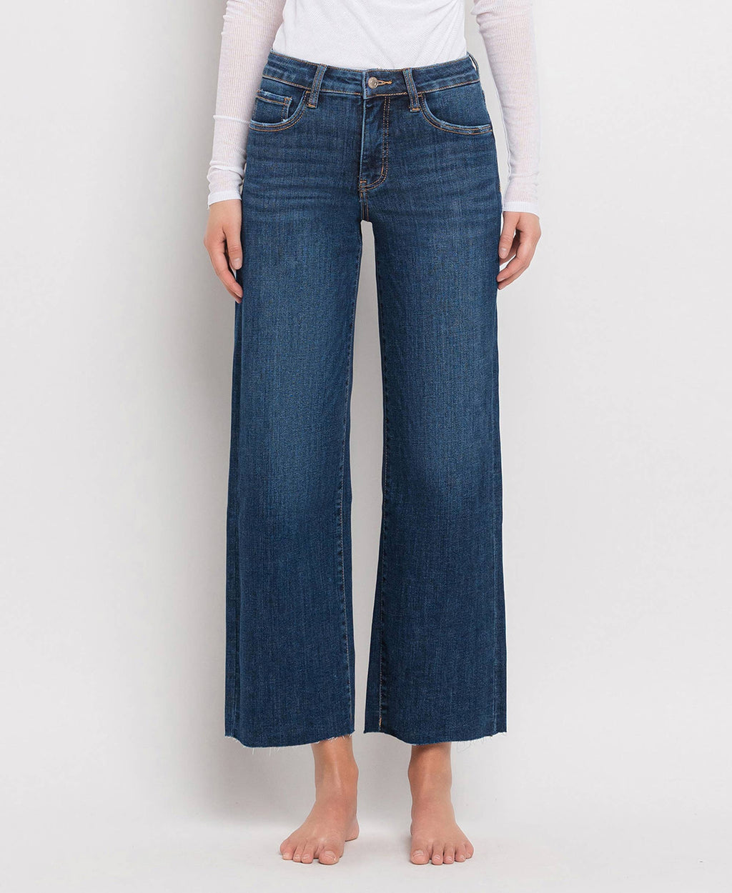 Women's mid-rise dark wash wide leg jeans featuring tummy control panels, comfort stretch denim, cropped length, and a raw hem.