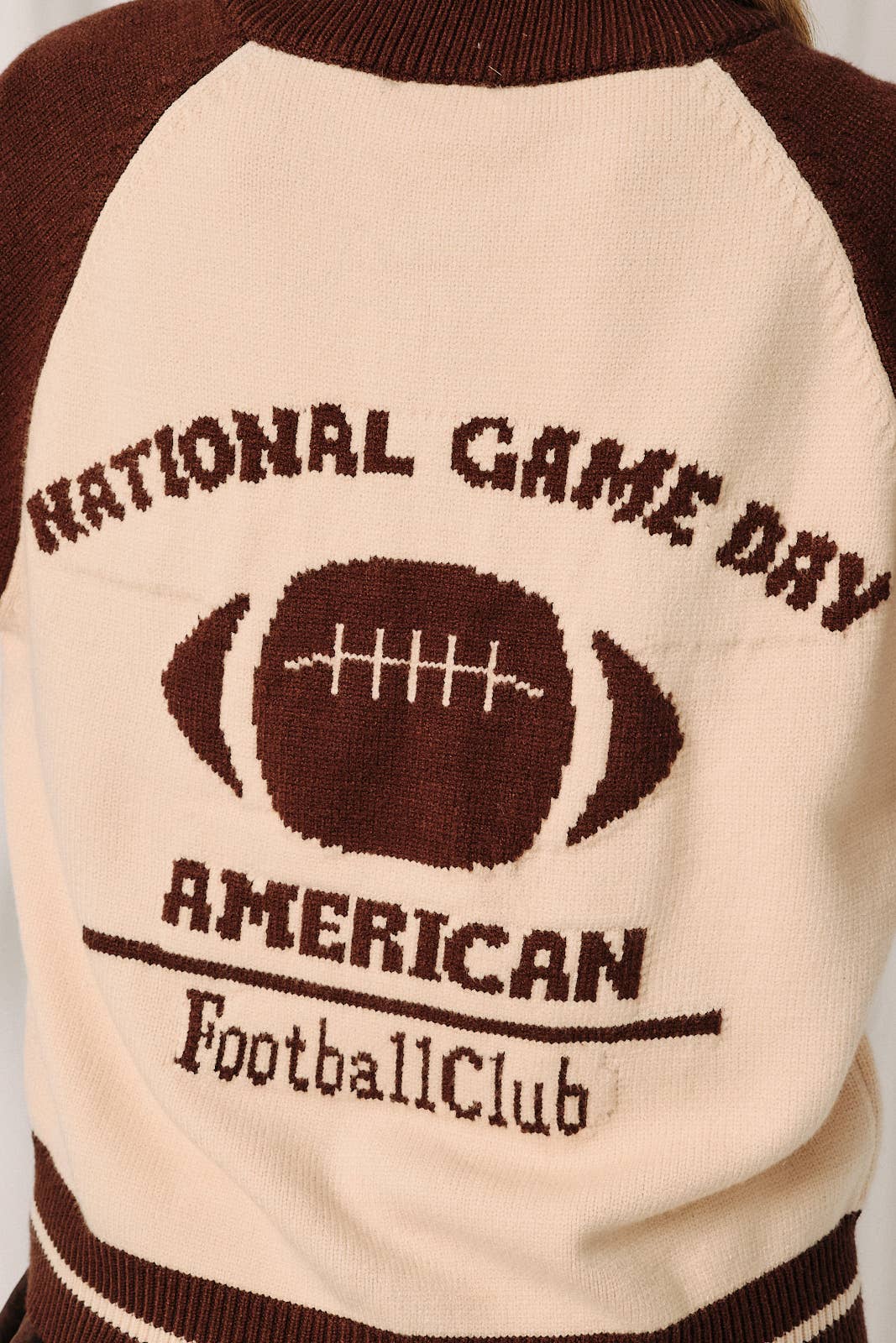 Soft cream knit fabric with brown contrast details on a cozy football-inspired cardigan.