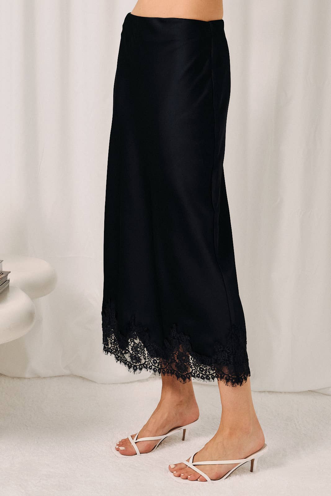 Side view of women's navy satin bias skirt showing the smooth drape and flattering midi length.