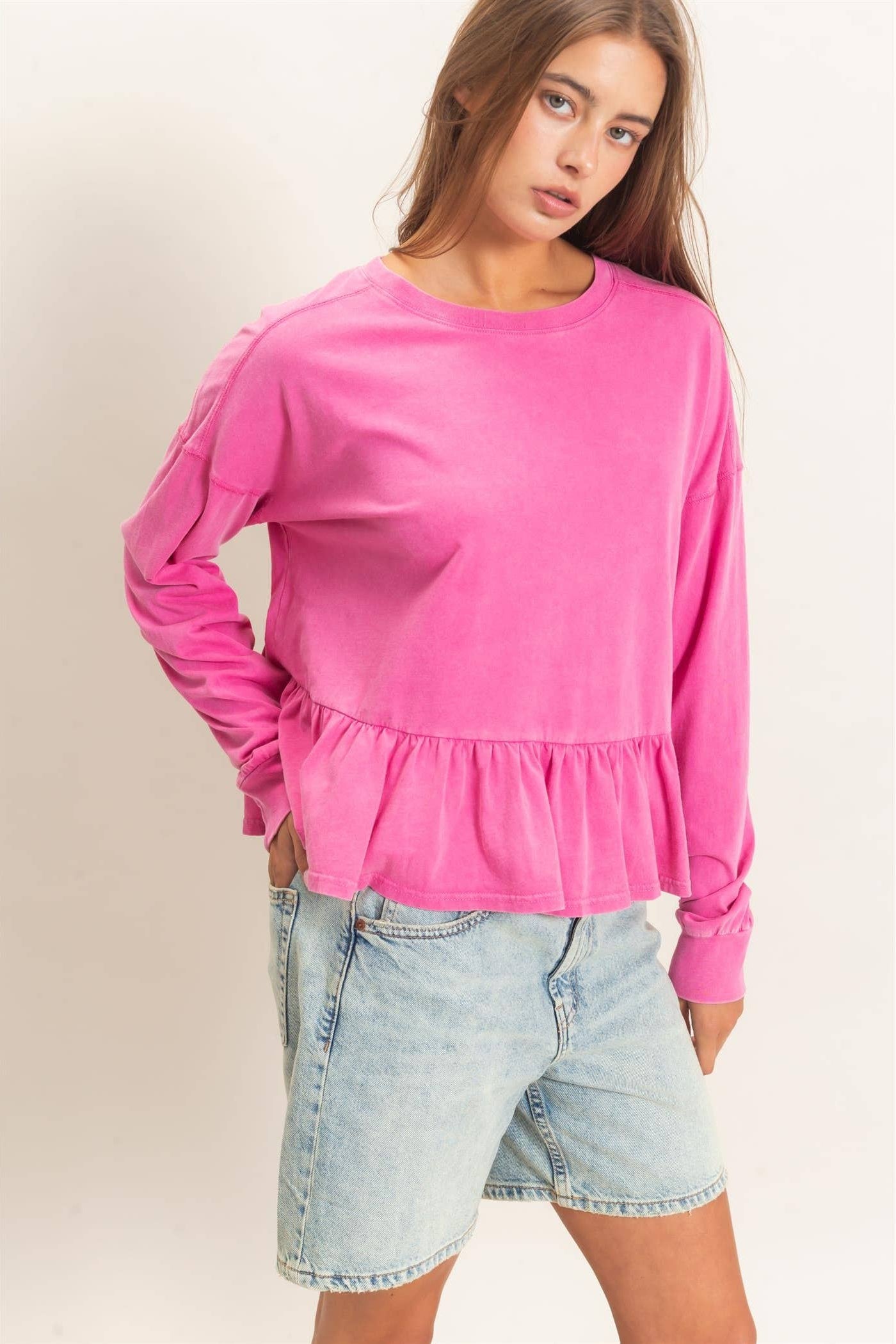 Women's peplum long sleeve top with crew neckline, relaxed fit, and ruffled hem.