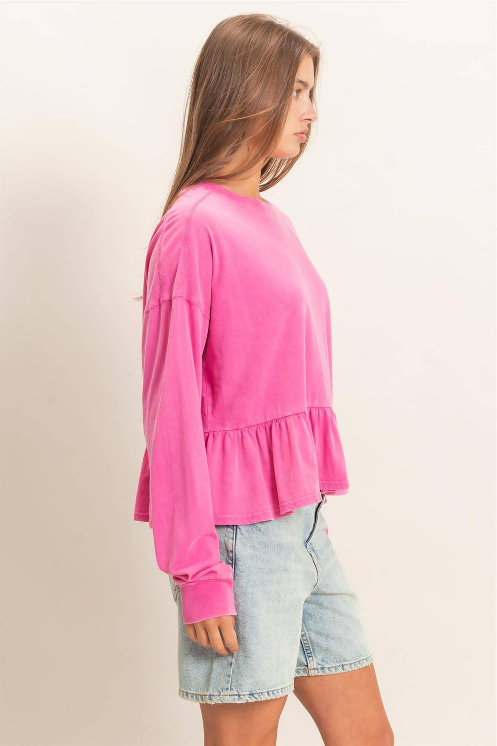 Side view of a women's peplum top featuring a flattering ruffle hem and relaxed silhouette.