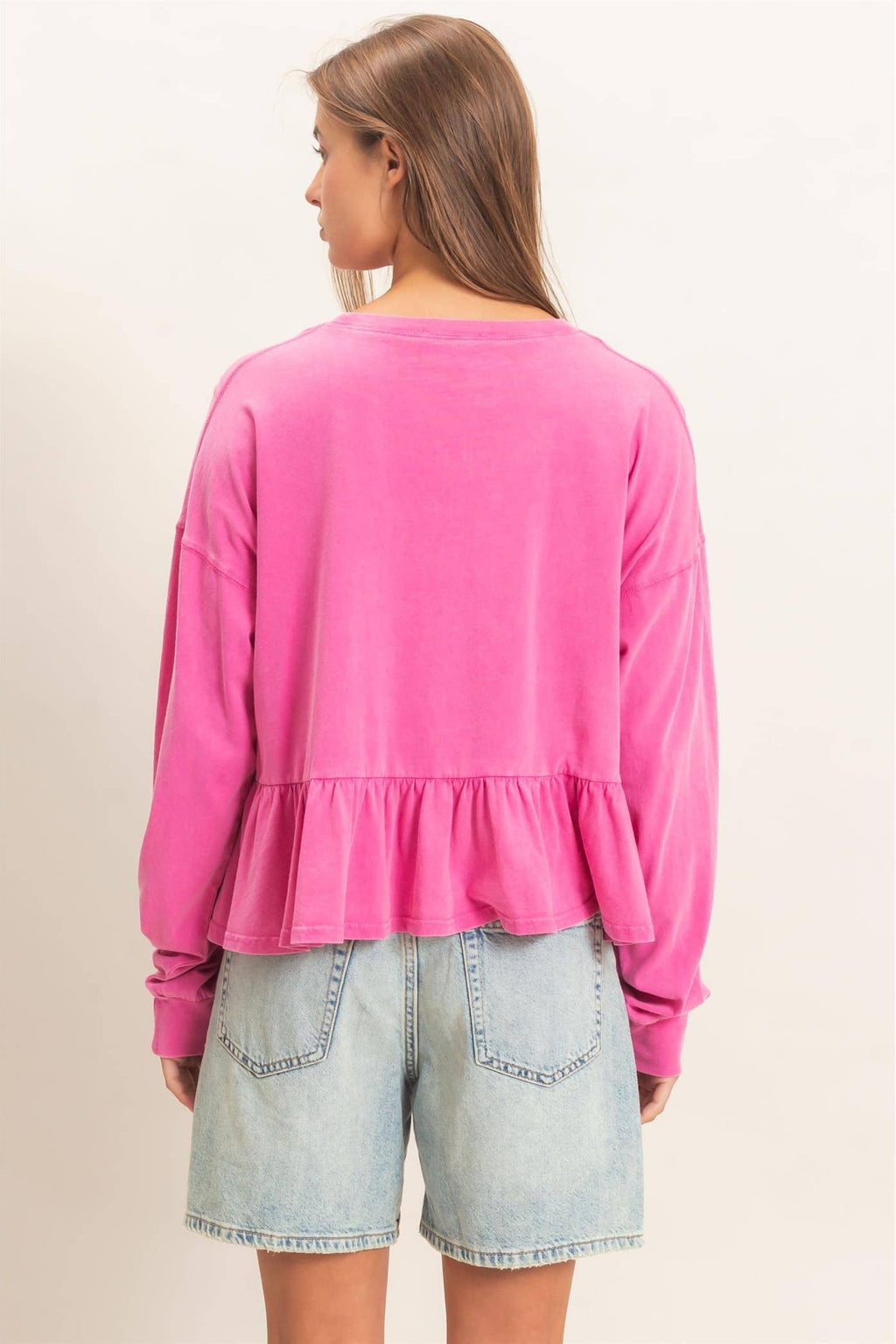 Back view of a long sleeve peplum top with an elegant relaxed fit.