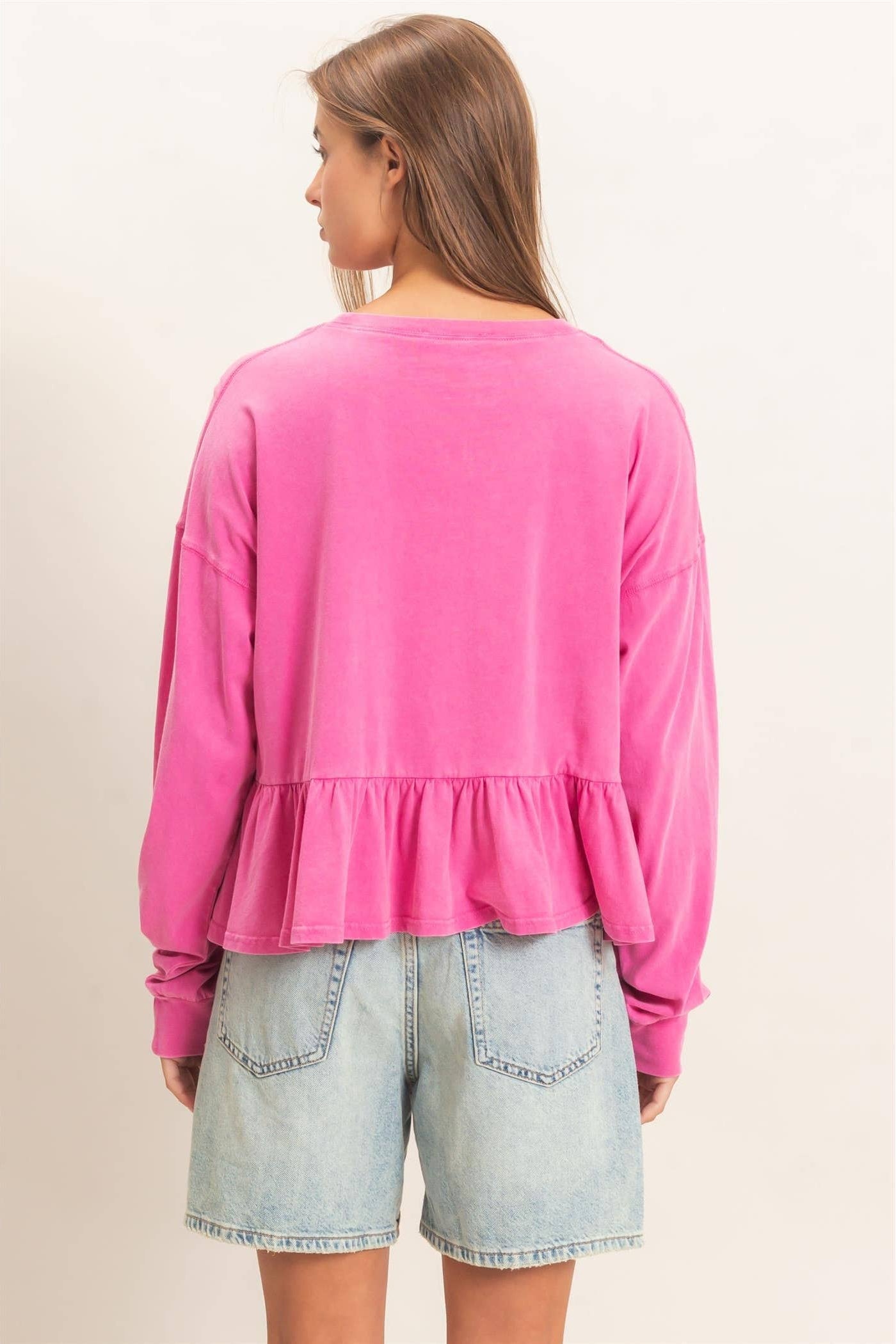 Back view of a long sleeve peplum top with an elegant relaxed fit.