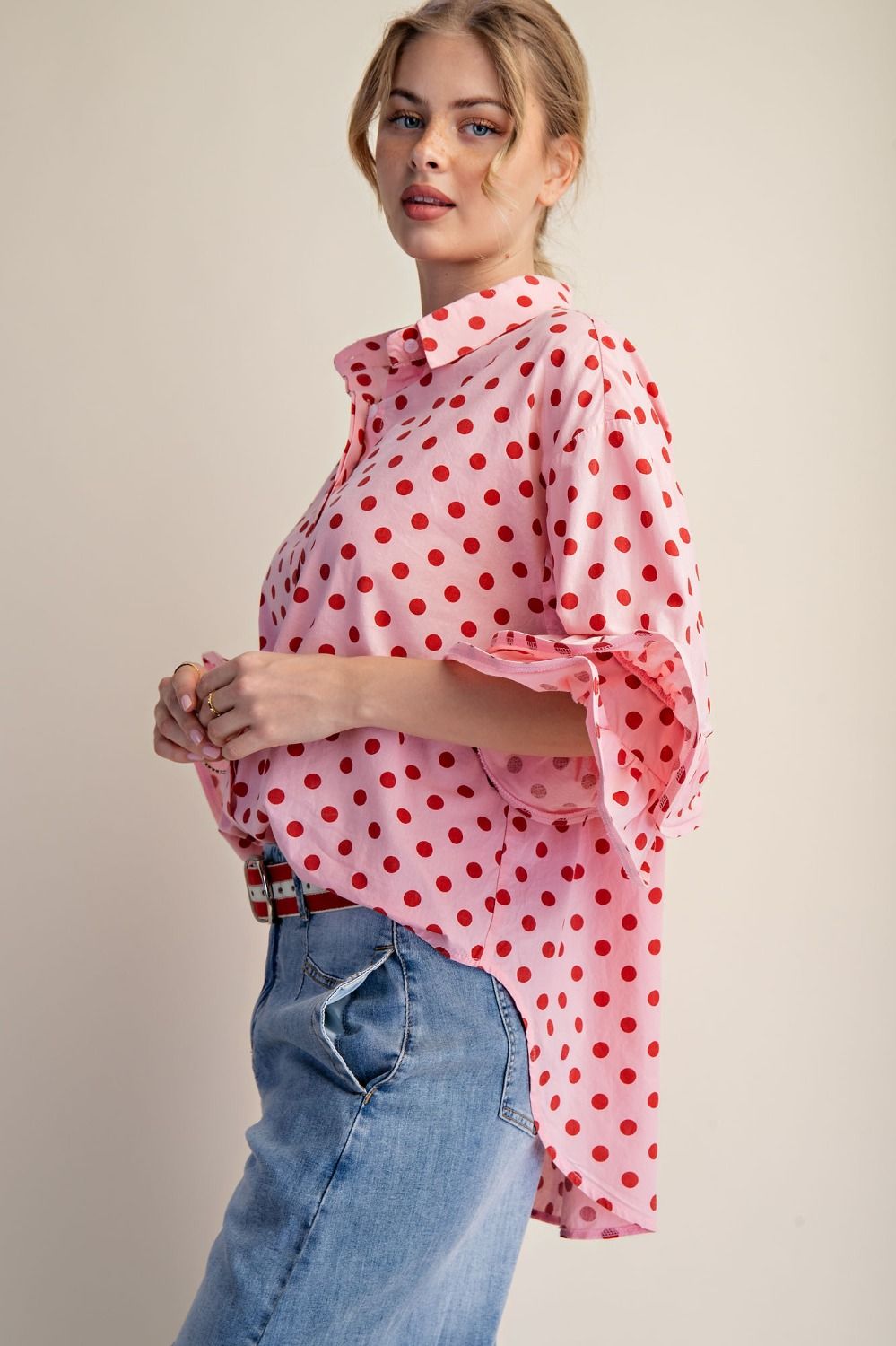 Side view of the lightweight cotton polka dot button-down blouse with a relaxed fit and longer back length.