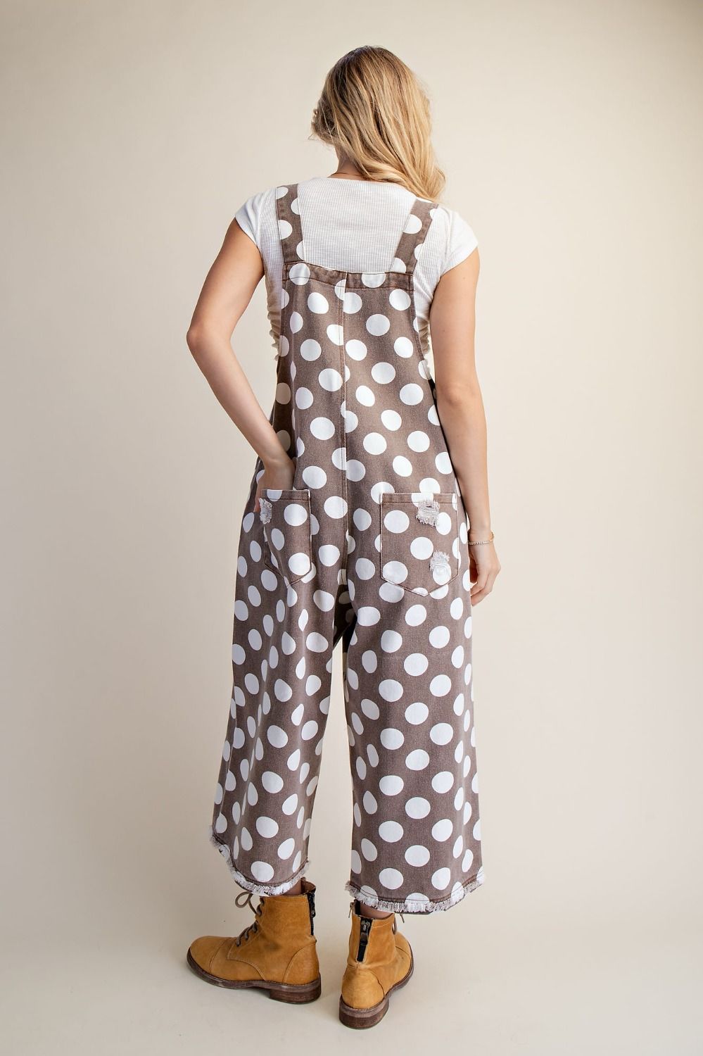 Back view of mocha brown wide leg overalls with an allover white polka dot print.
