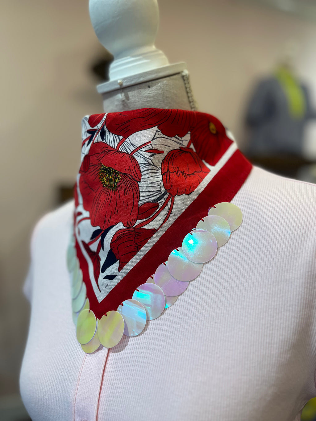 Close-up of white sequins on a red floral print bandana.