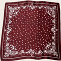 Maroon bandana with white polka dot and paisley patterns on a beige background