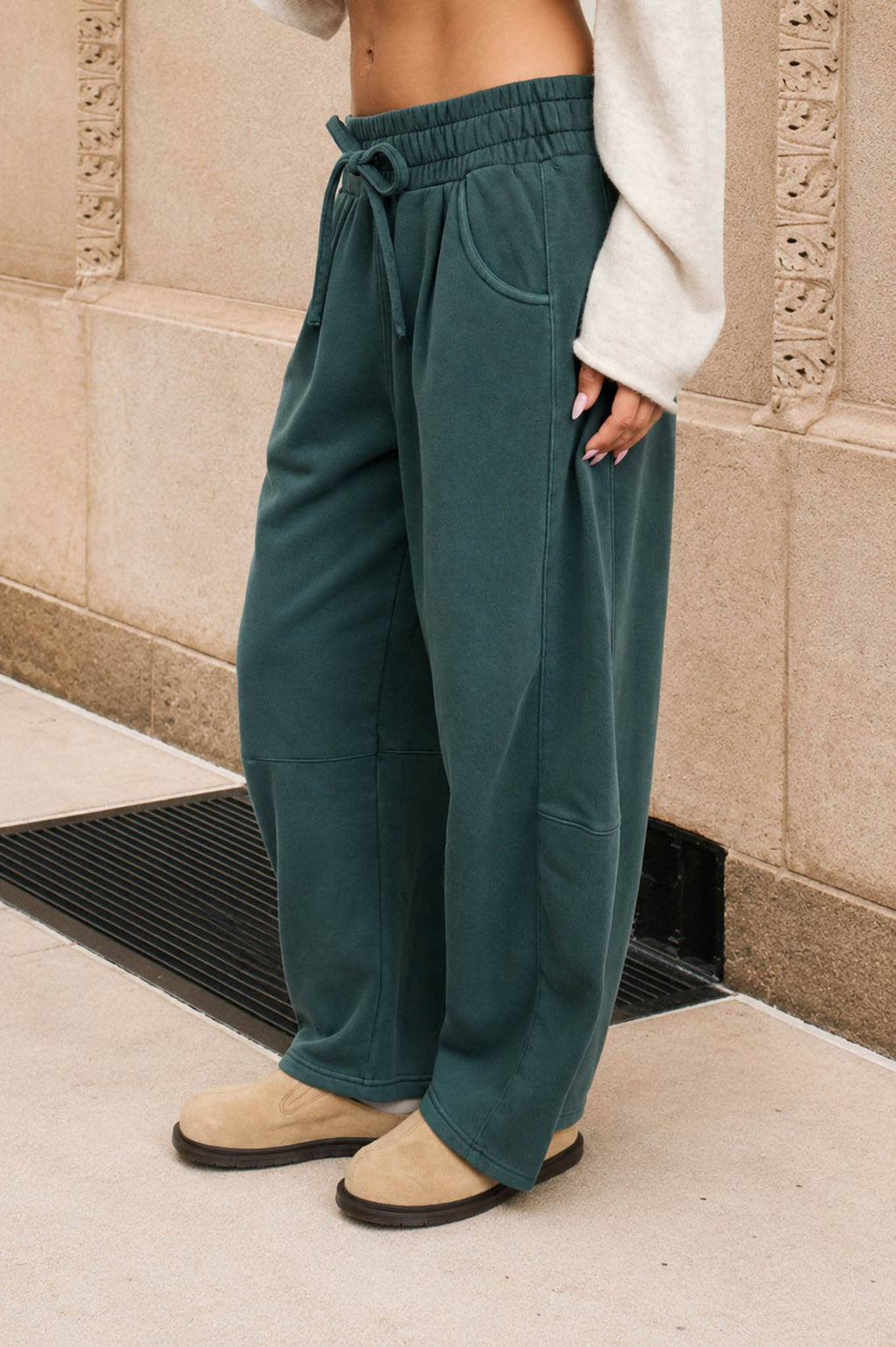 Side view of women's washed dark green wide leg sweatpants featuring side seam details and roomy pockets.