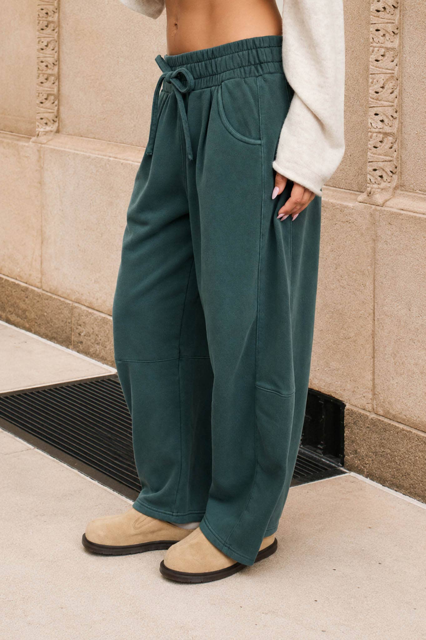 Side view of women's washed dark green wide leg sweatpants featuring side seam details and roomy pockets.