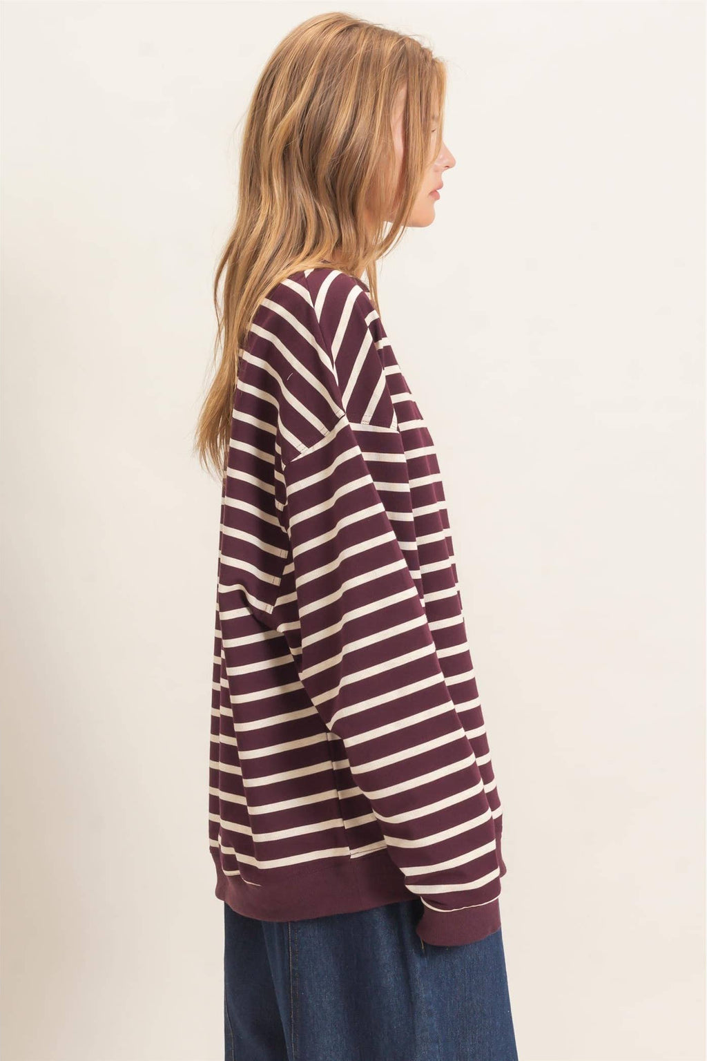 Model wearing a burgundy and white striped knit pullover styled with high-waisted jeans for a casual fall outfit.