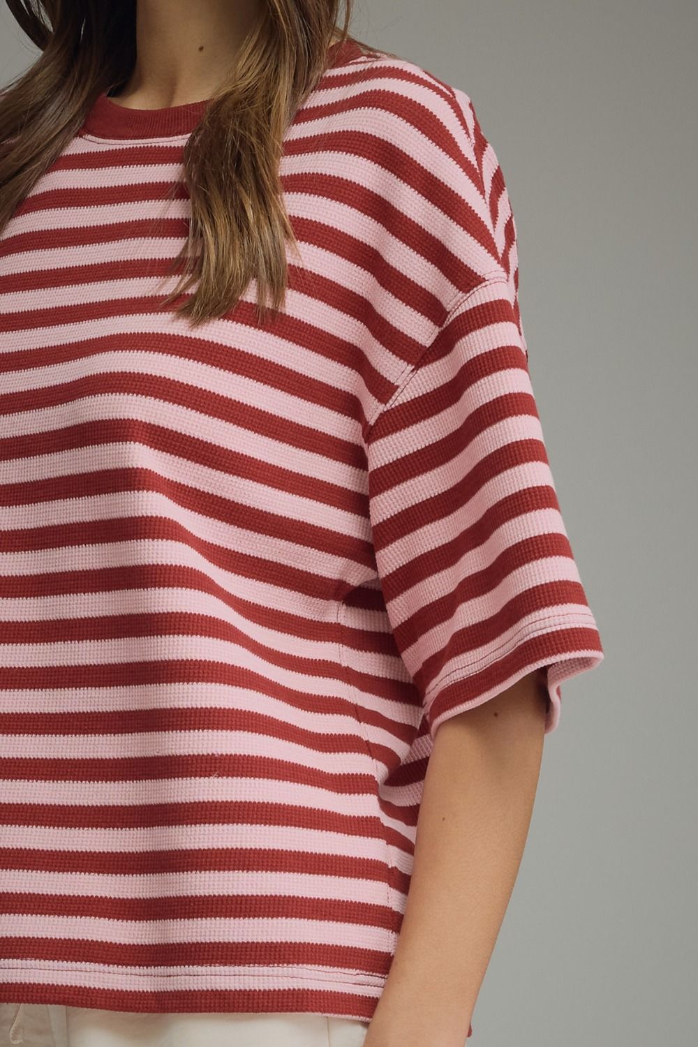 Side view of a burgundy and pink striped ribbed knit top with short sleeves.