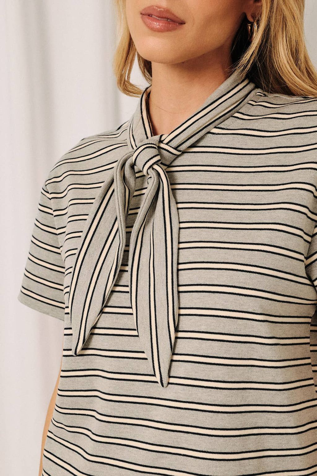 Close-up of gray, navy, and white stripe pattern on a lightweight women's boutique top.
