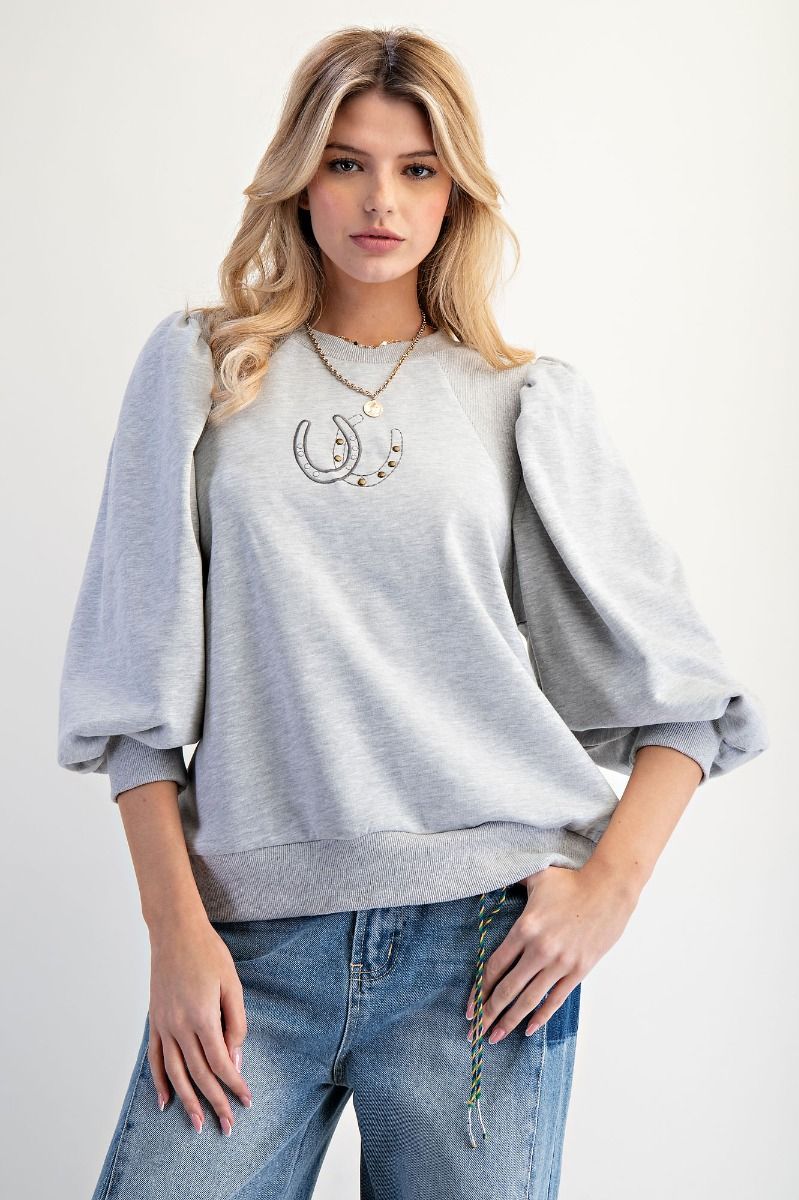 Woman wearing a gray sweatshirt with a design and blue jeans on a white background